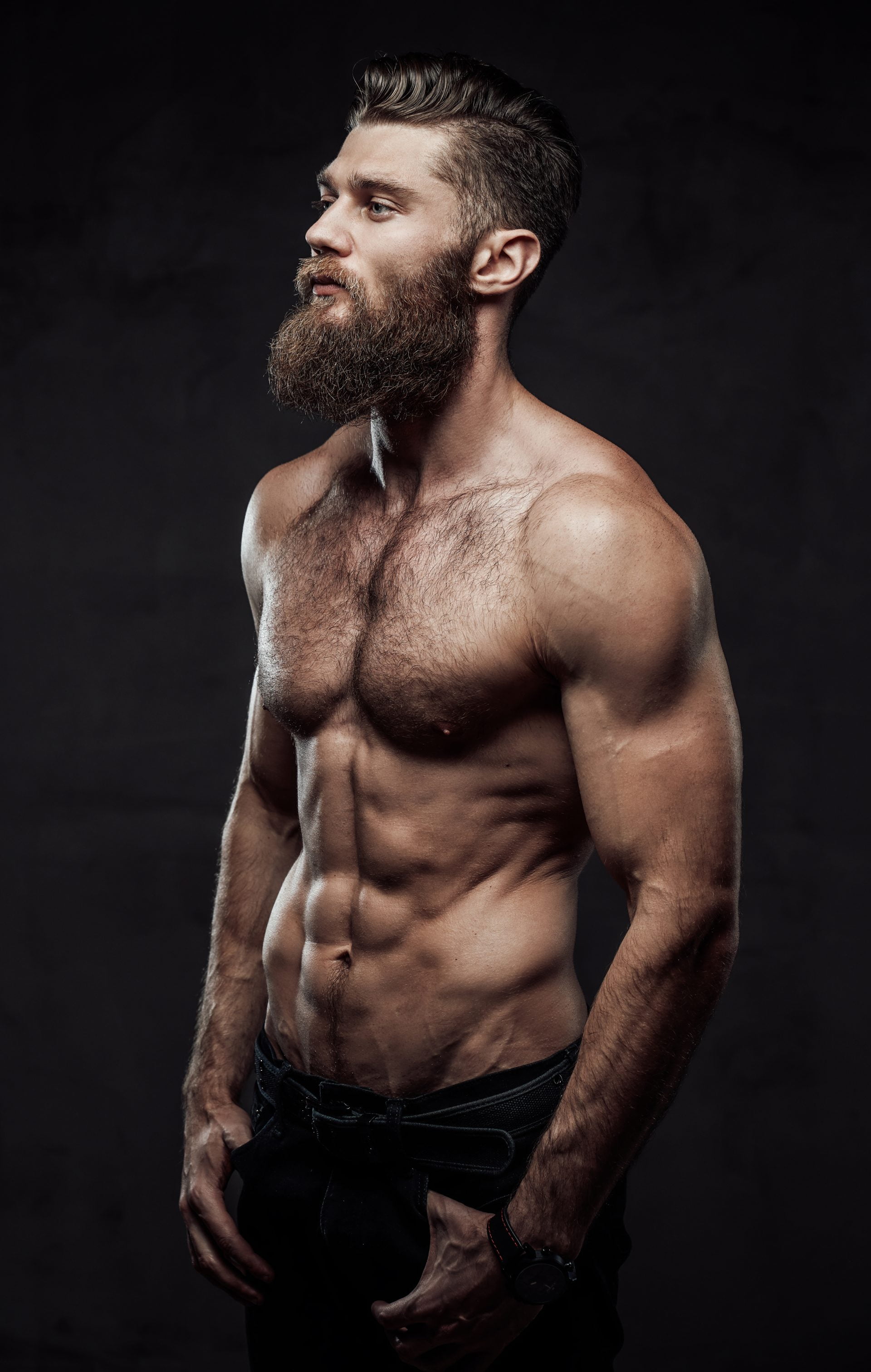 Bearded guy with naked torso posing in dark background