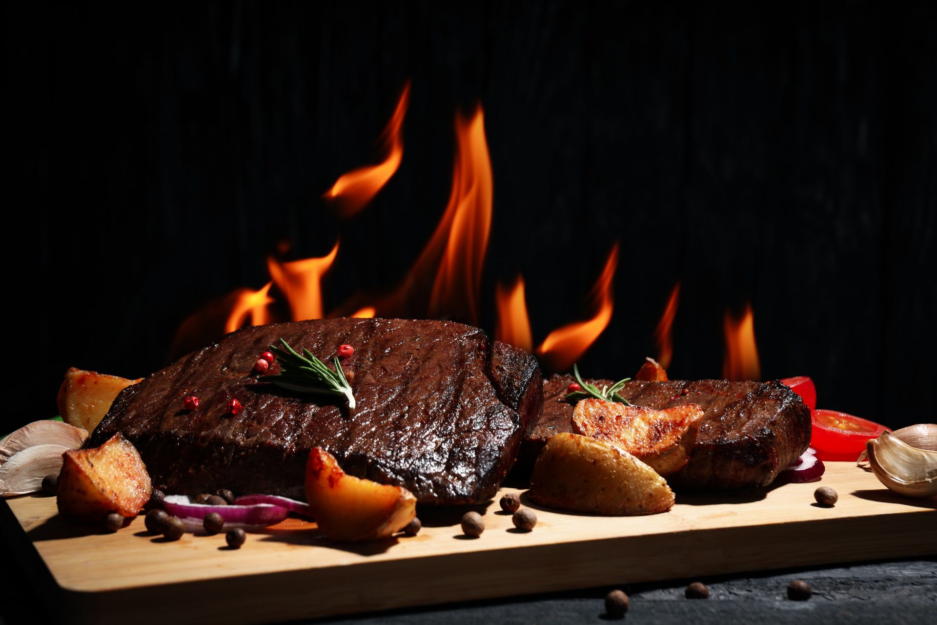 Concept of tasty food with beef steaks on dark wooden table