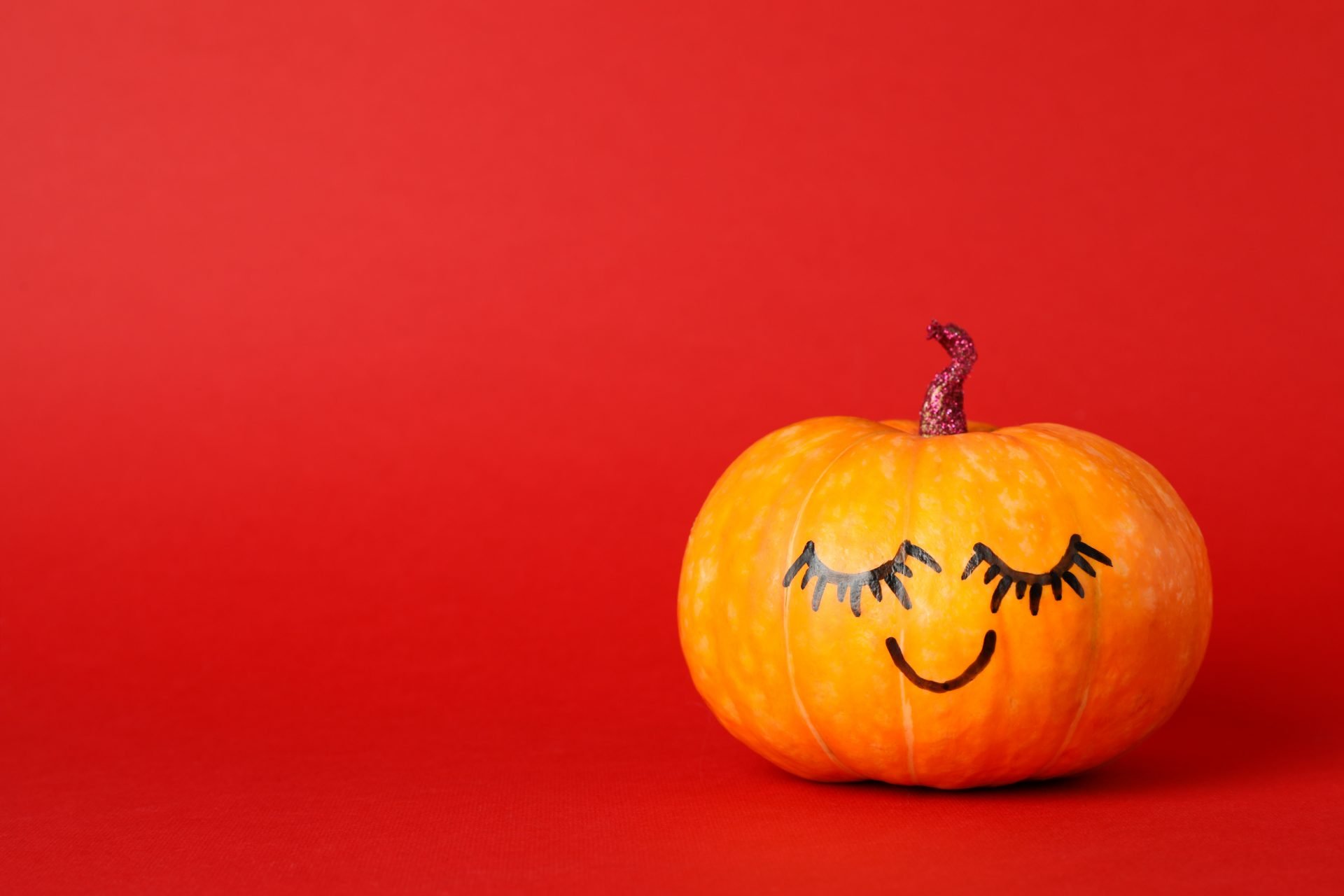 Pumpkin with smile on red background, space for text